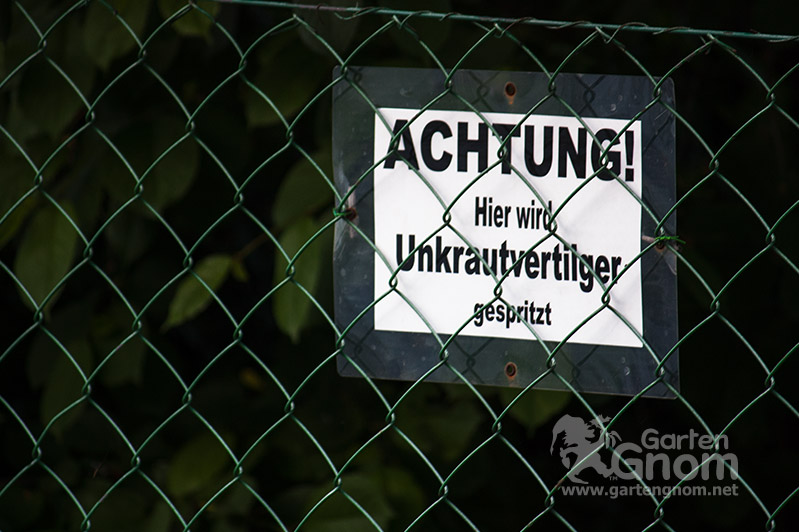 Schild mit Aufschrift: Achtung! Hier wird Unkrautvertilger gespr